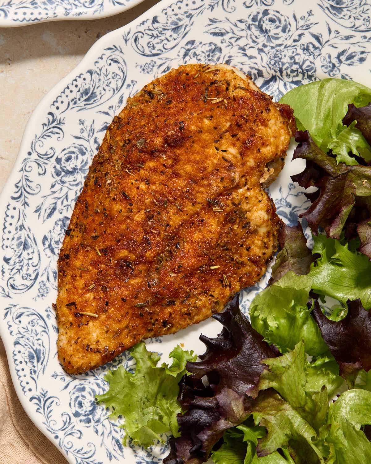 Overhead of an air fried chicken cutlet on a plate.