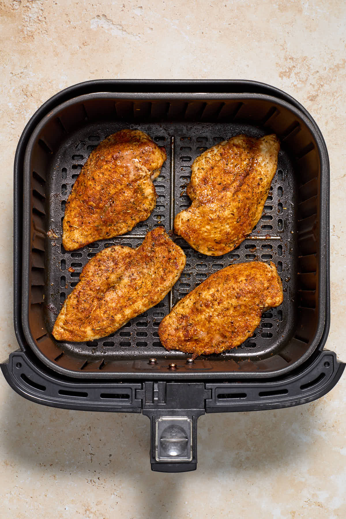 Overhead of 4 pieces of air fried chicken in an air fryer basket.