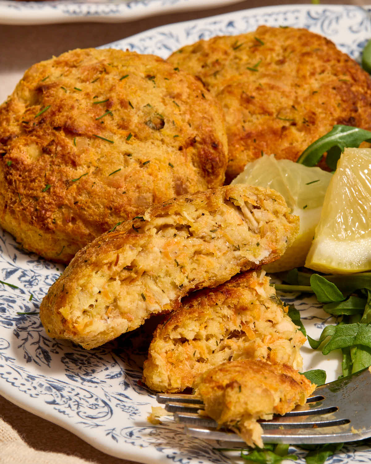 Side view of tuna cakes served on a plate with one cut in half.