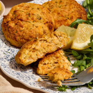 Side view of a tuna cake on a plate with a bite removed.