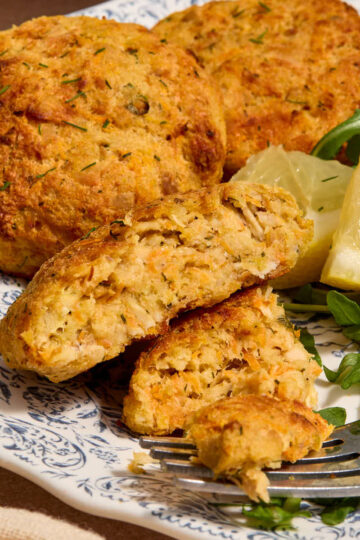 Side view of a tuna cake on a plate with a bite removed.