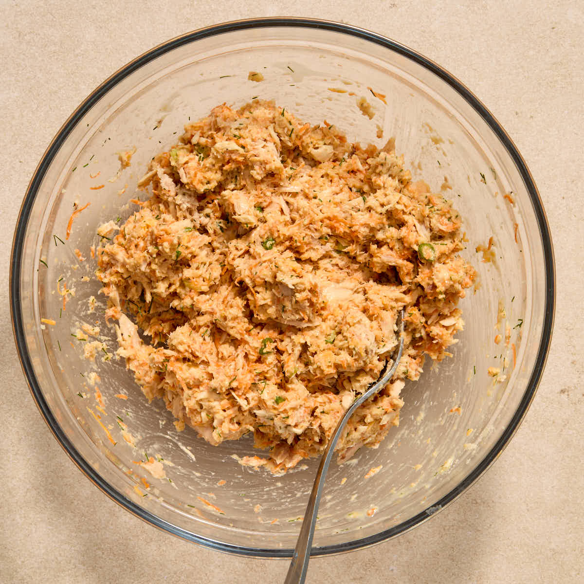 All of the tuna cake ingredients mixed together in a bowl with a fork.