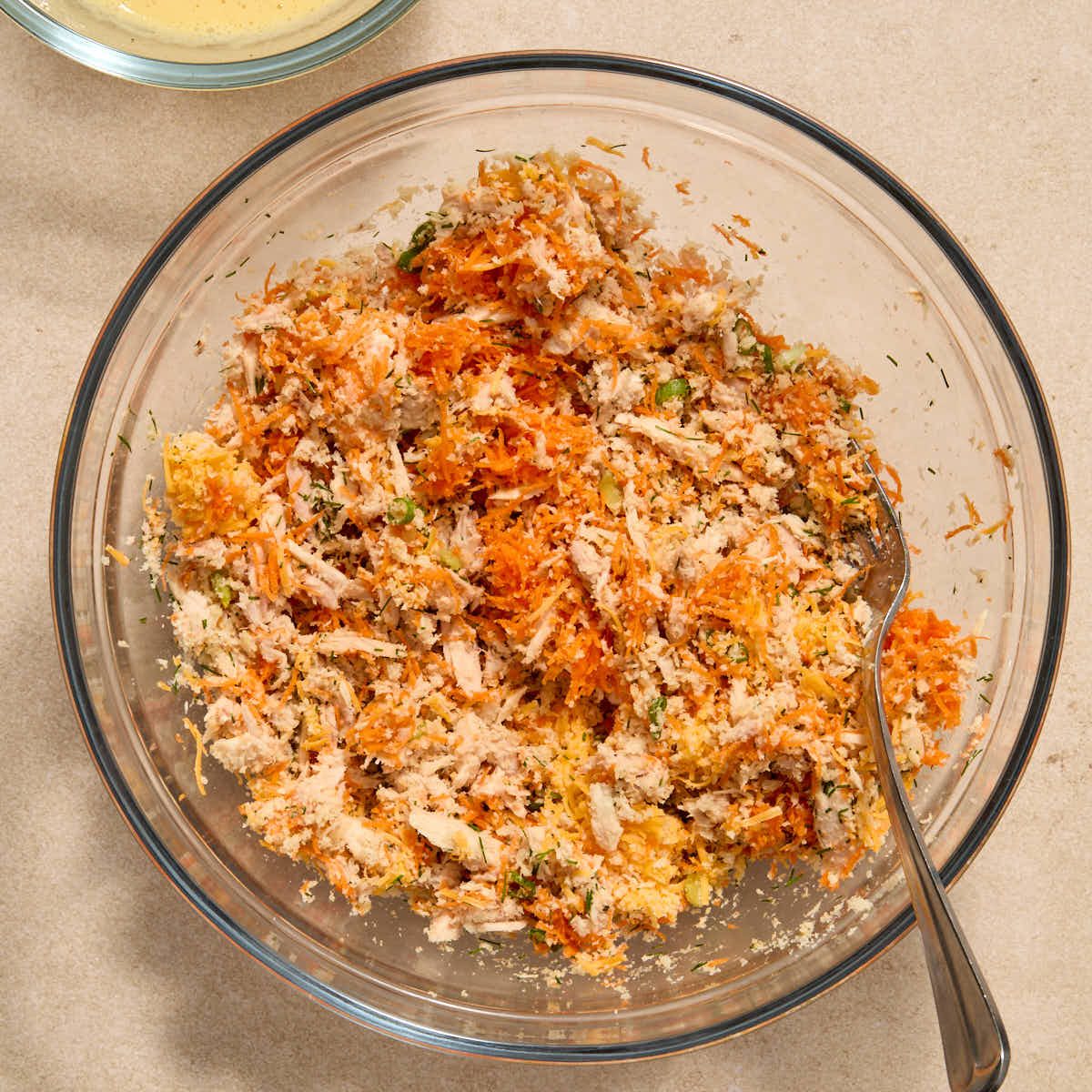 Tuna, carrot, cheese, panko crumbs, onion and dill stirred together in a bowl.