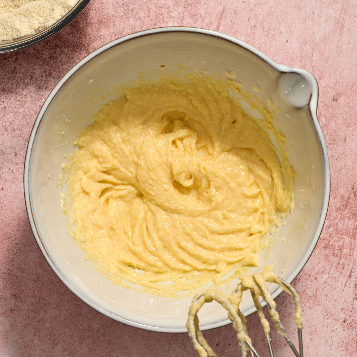 Eggs and extracts mixed into the butter/sugar mixture in a white bowl.