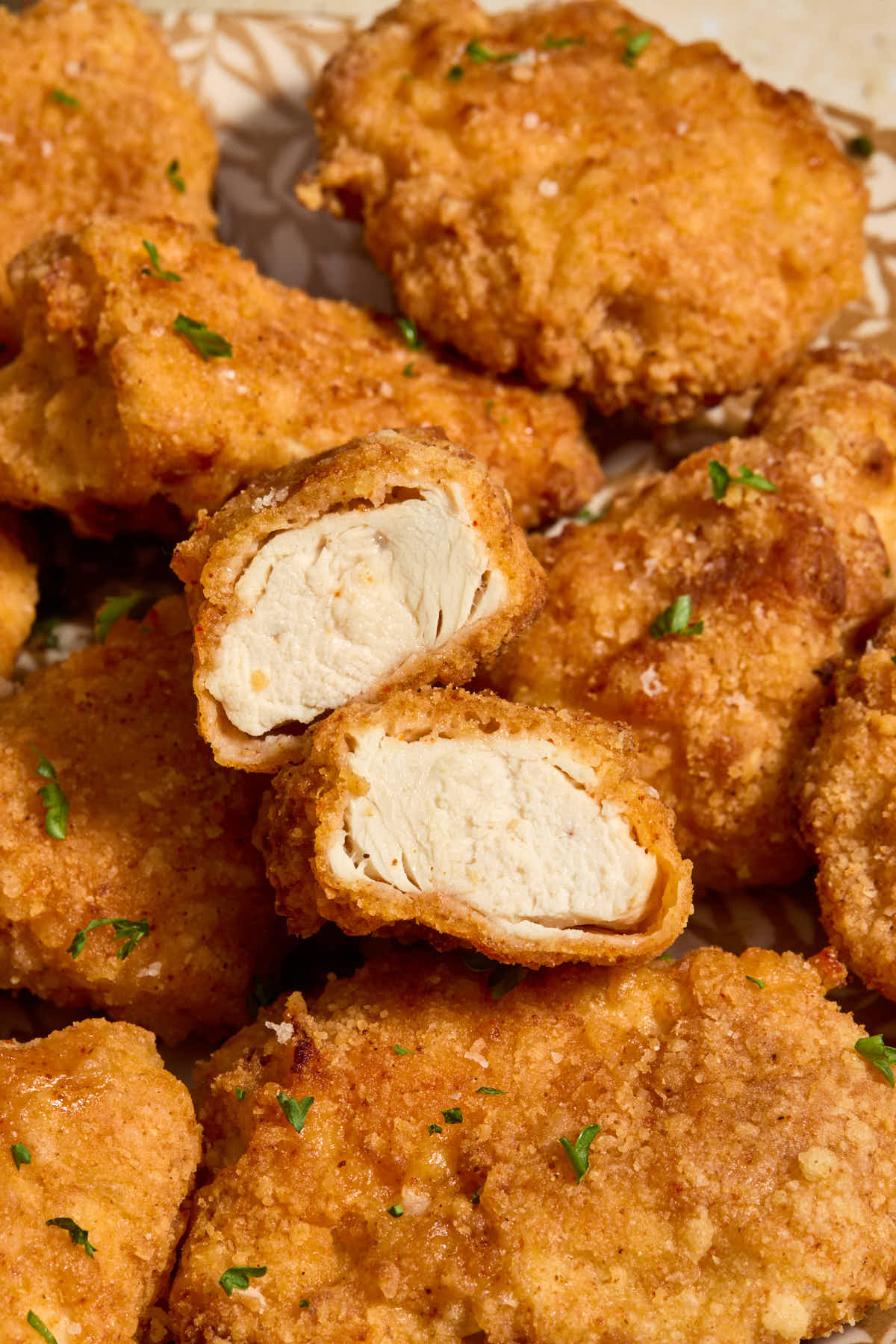 Close up of a boneless wing cut in half to show the cooked chicken inside.