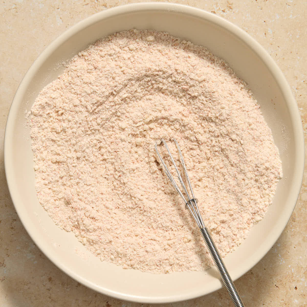Flour and parmesan coating mixed together in bowl with a whisk.