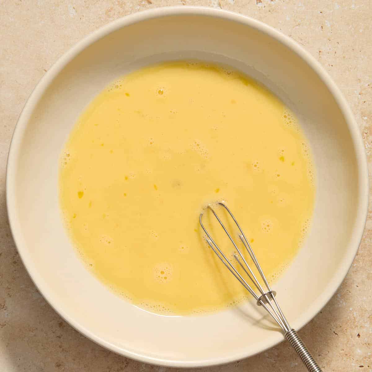 Eggs and milk whisked together in a shallow bowl.