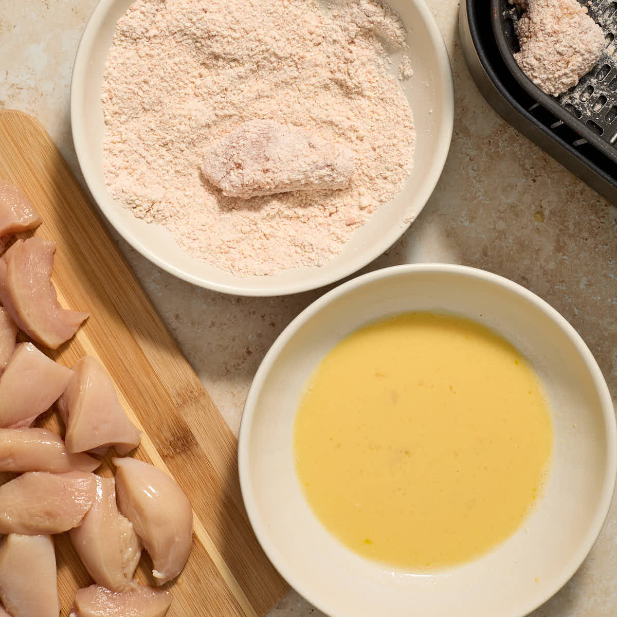 Piece of chicken being coated in the flour mixture.