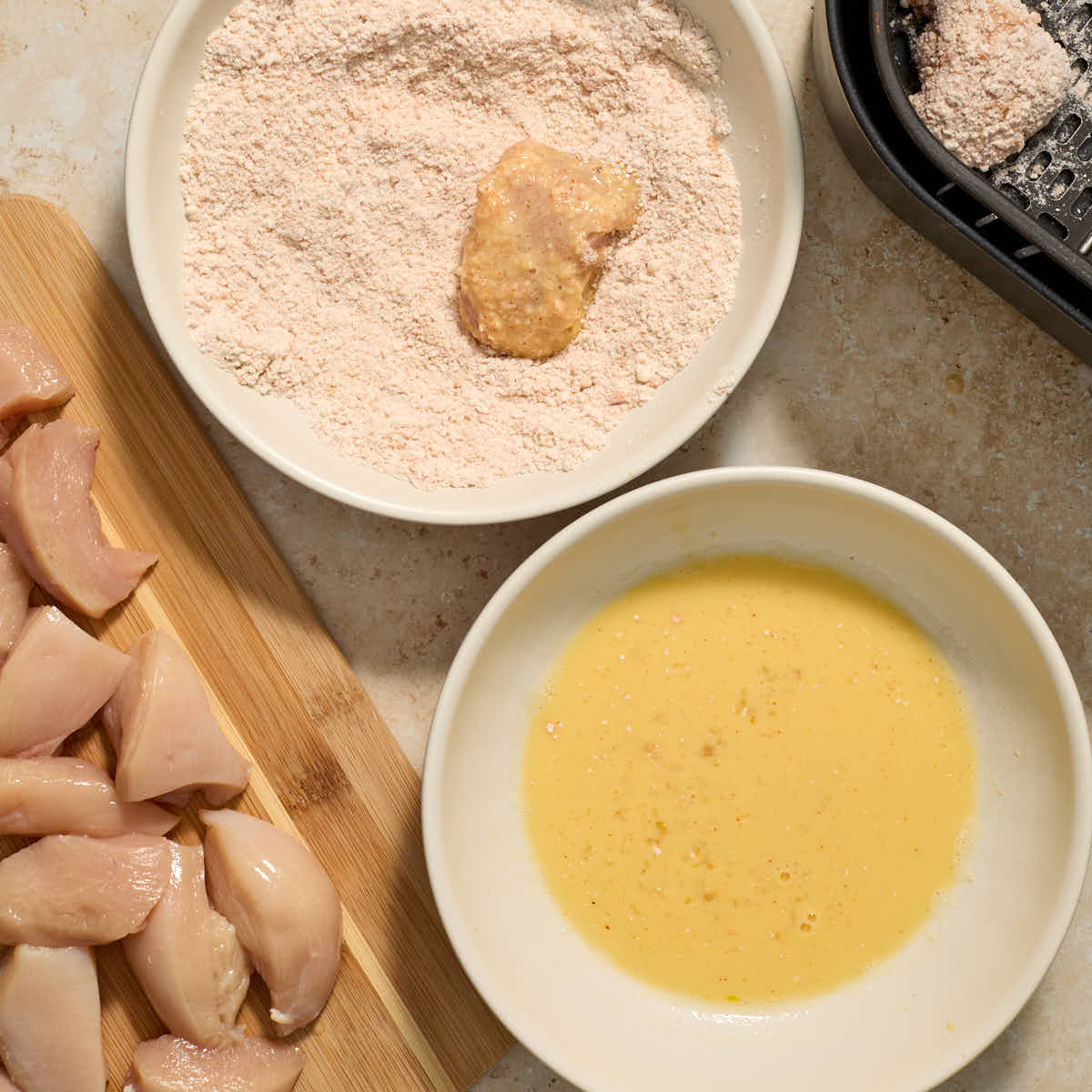 Piece of chicken being coated in a second layer of the flour mixture.