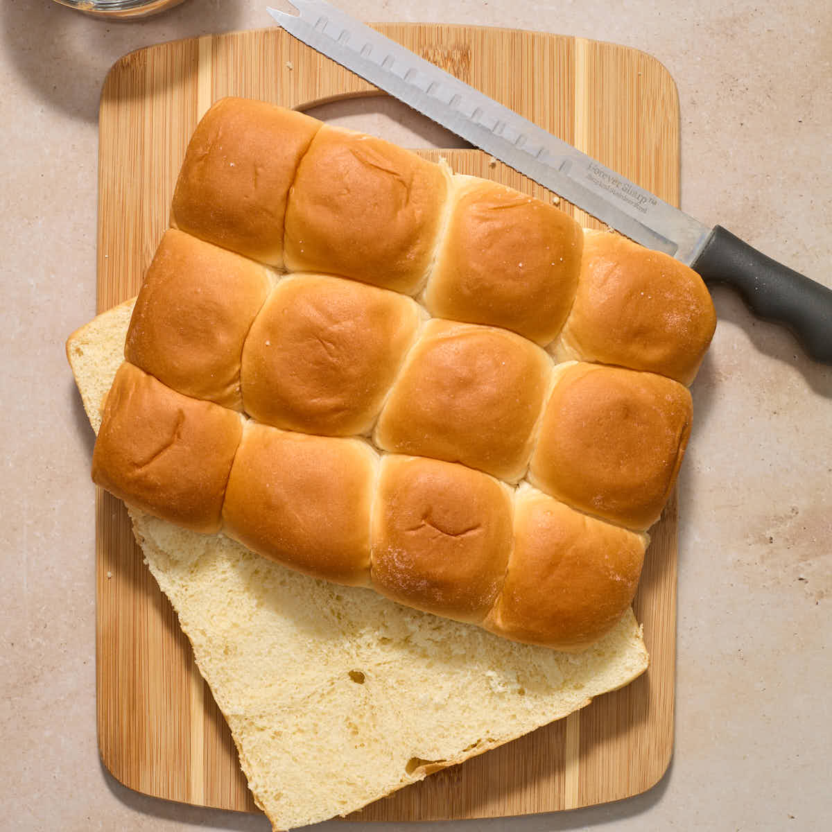 Package of sweet rolls cut in half horizontally on a wooden cutting board.
