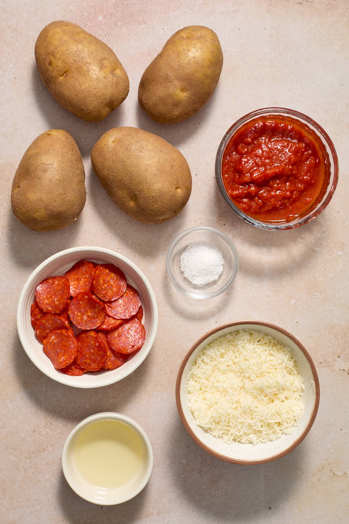 Ingredients to make pizza potato skins arranged individually on a work surface.