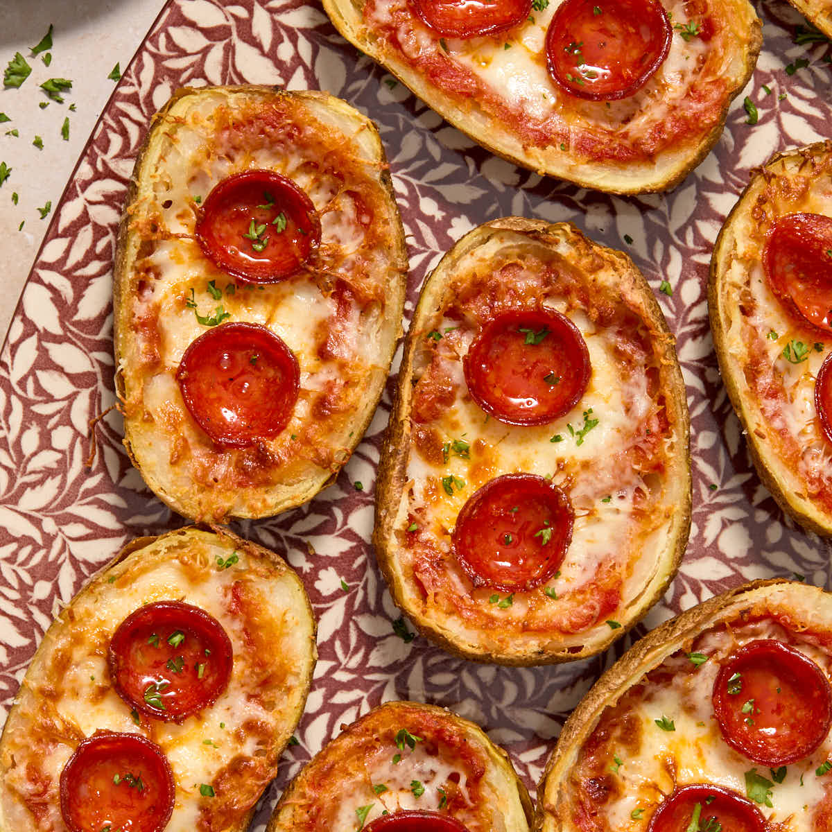 Air Fryer Pizza Potato Skins arranged on a platter and topped with chopped herbs.