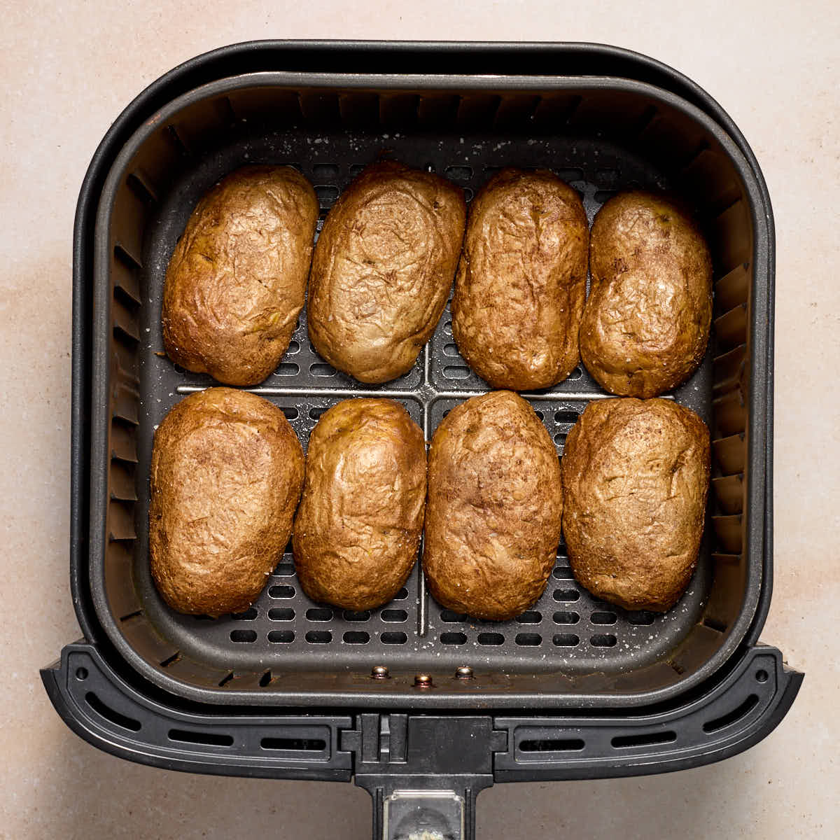 Potato skins arranged in an air fryer basket skin side up.