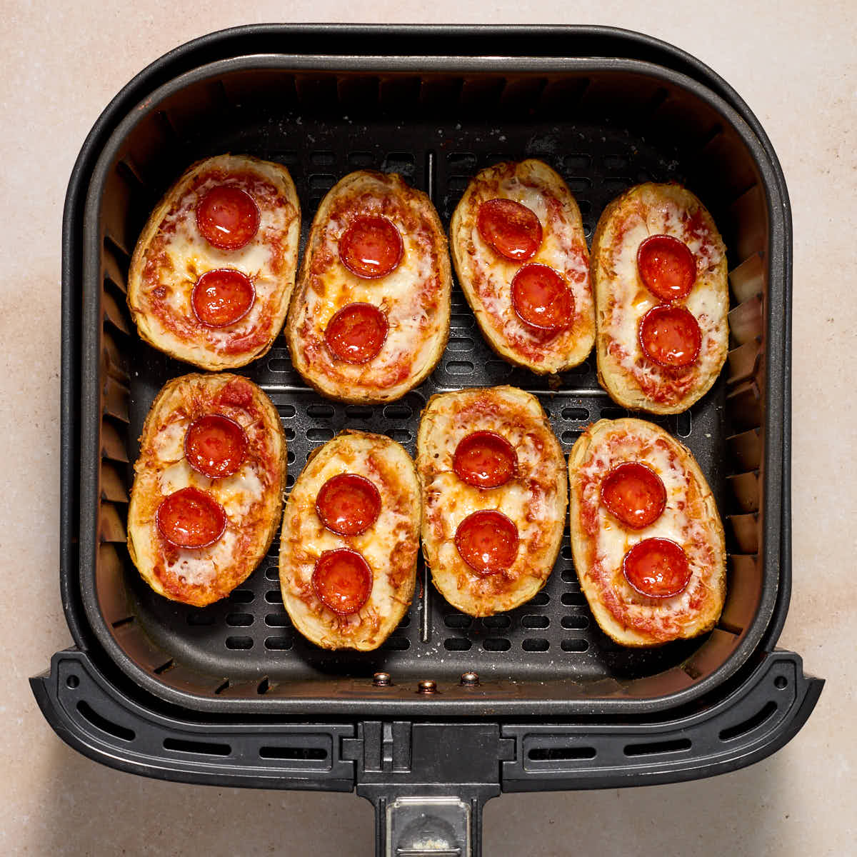Air fried potato skins in the air fryer basket.