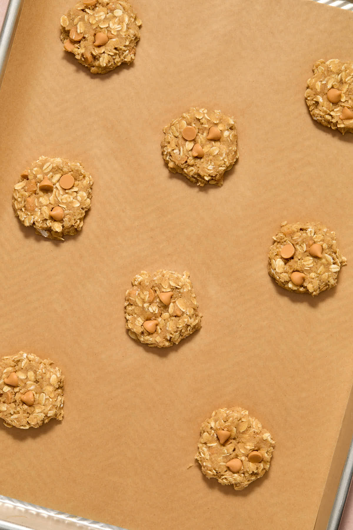 Unbaked cookies arranged on a parchment lined baking sheet.