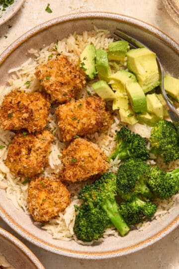 Air fryer breaded salmon bites served in a bowl with rice, broccoli and avocado.