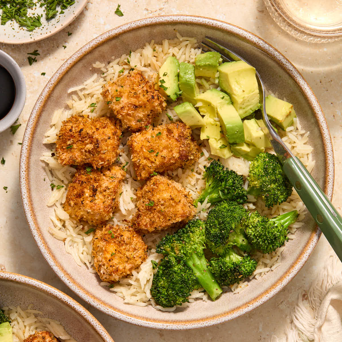 Air fryer breaded salmon bites served in a bowl with rice, broccoli and avocado.