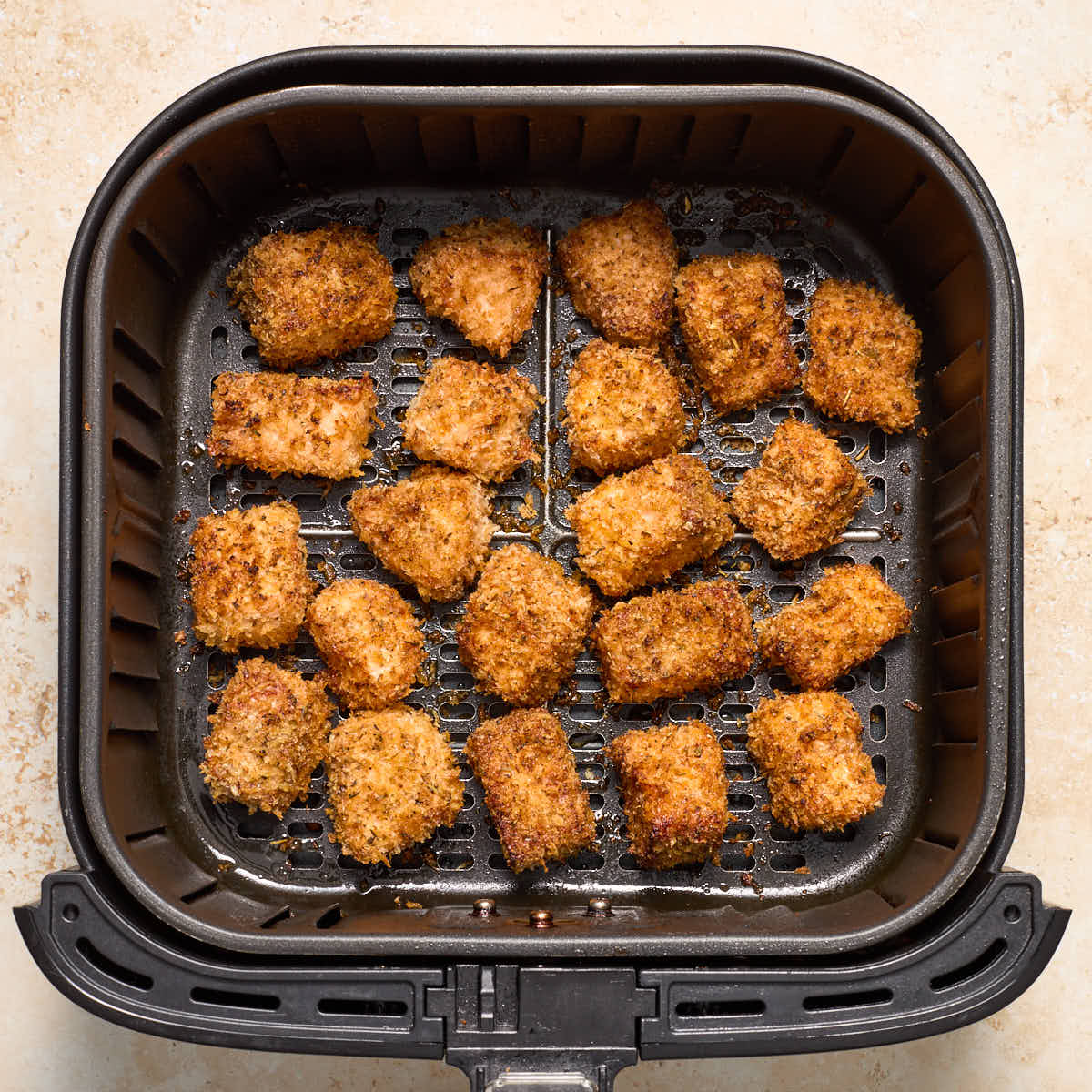 Air fried salmon bites in an air fryer basket.
