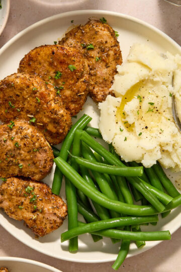 Overhead of pork medallions served on a plate with mashed potatoes and green beans.