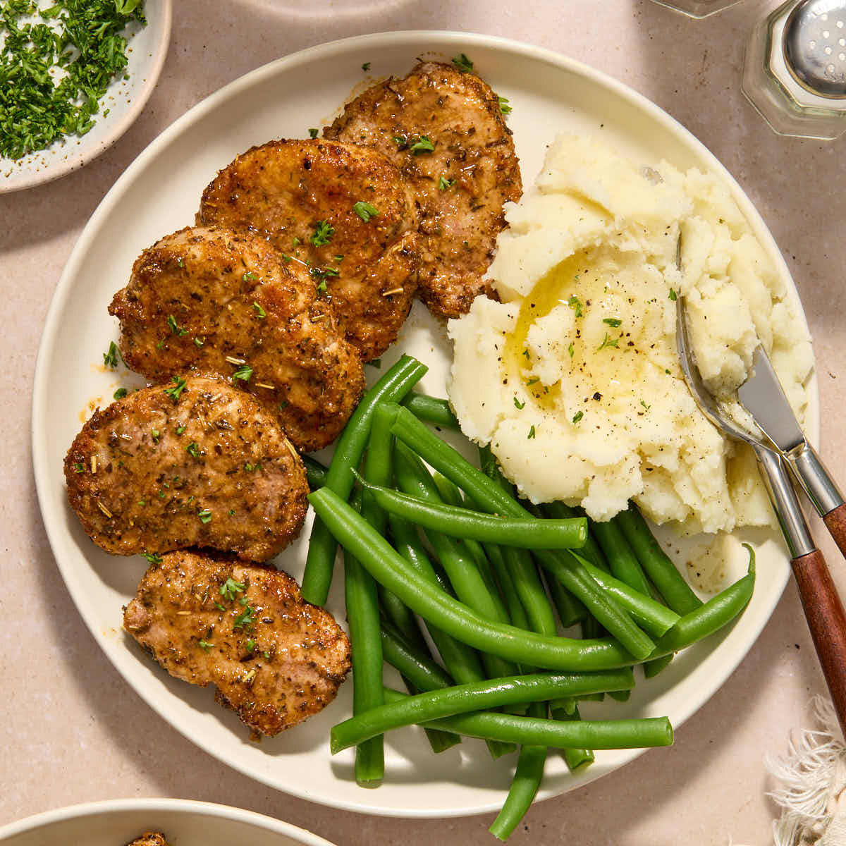 Overhead of pork medallions served on a plate with mashed potatoes and green beans.