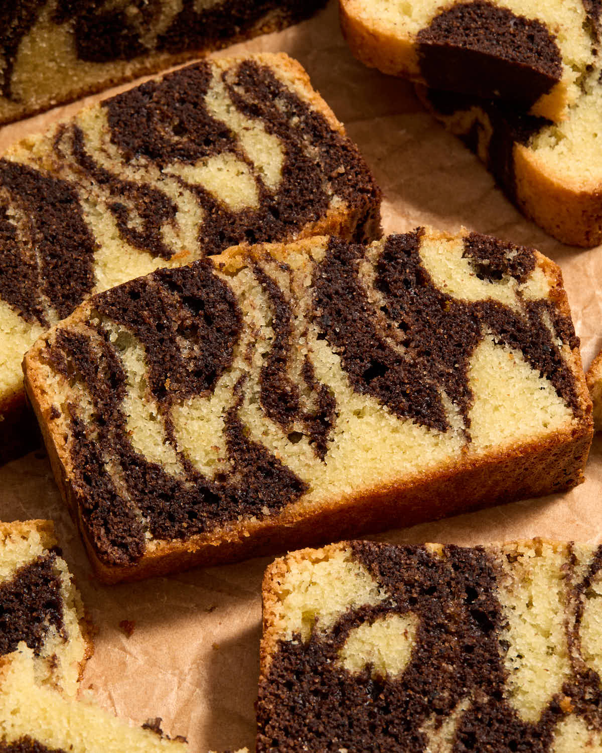 Angled view of slices of marble loaf arranged on brown parchment paper.