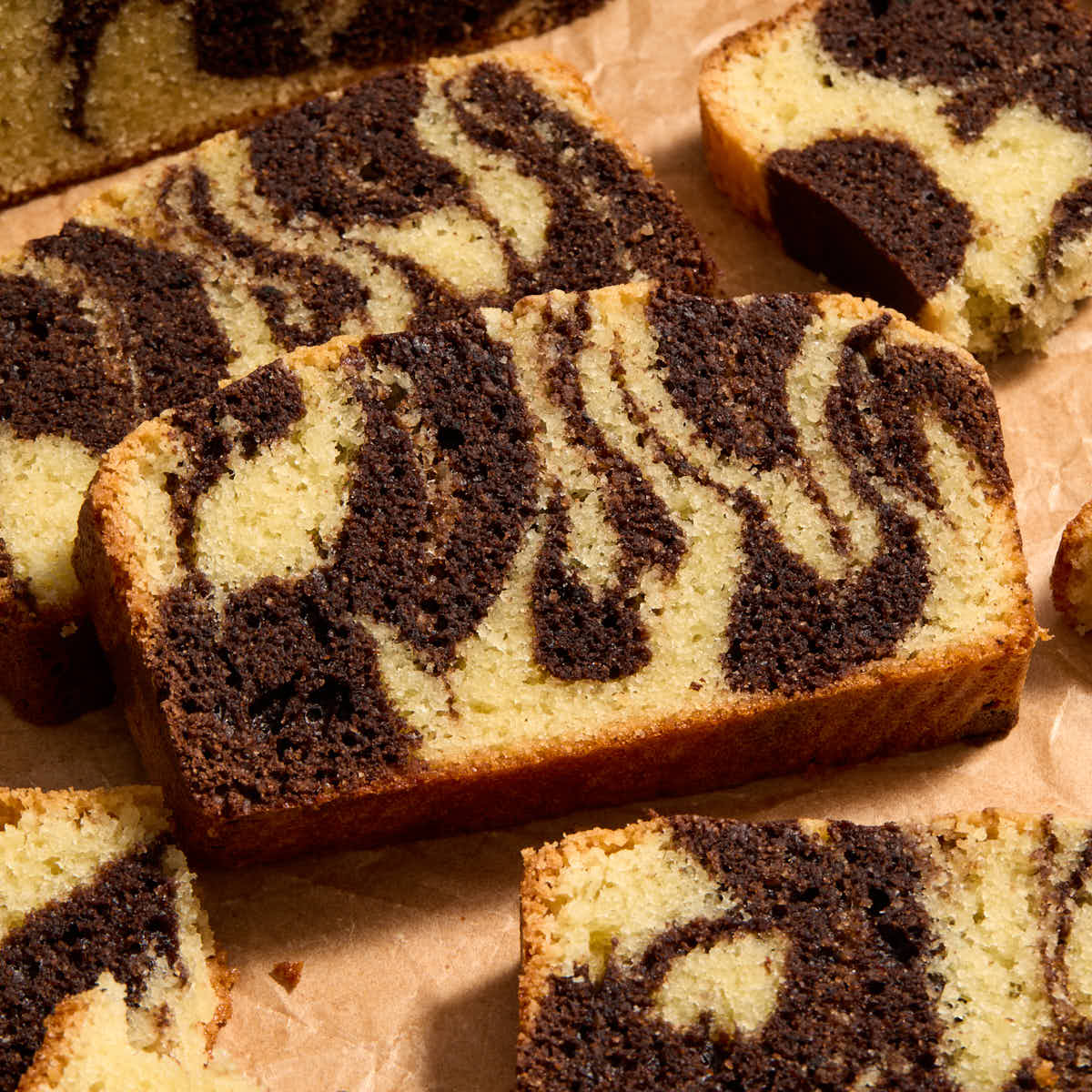 Close up of slices of almond flour chocolate marble loaf on brown parchment paper.