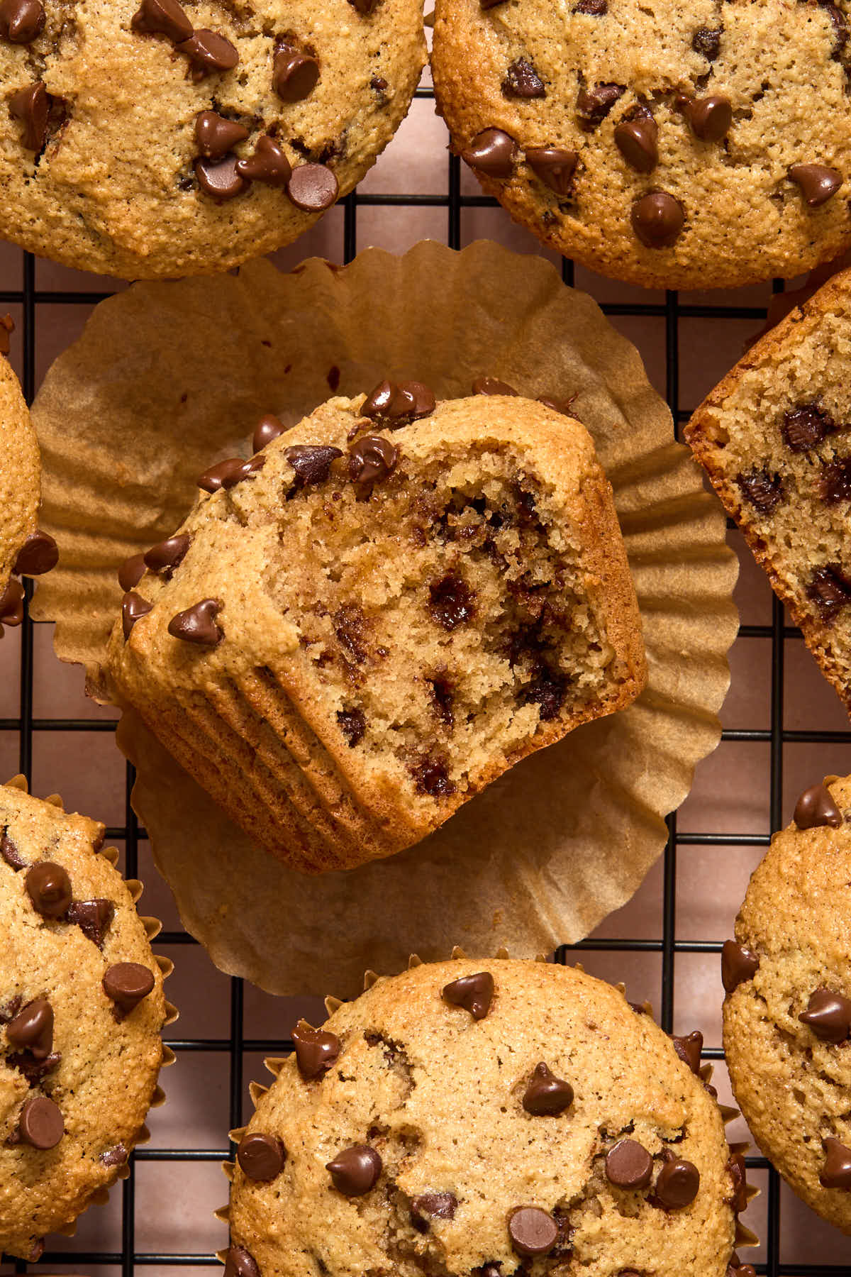 Overhead of muffins on a wire rack with one turned on its side with a bite removed.