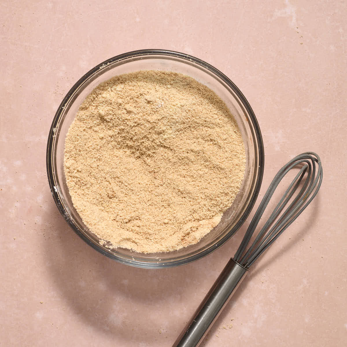Dry ingredients mixed together in a bowl with a whisk resting on the side.