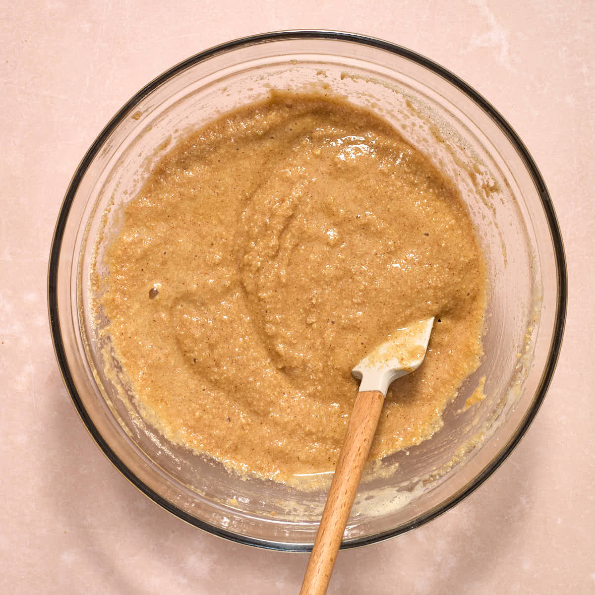 Muffin batter stirred together in a glass bowl with a spatula.
