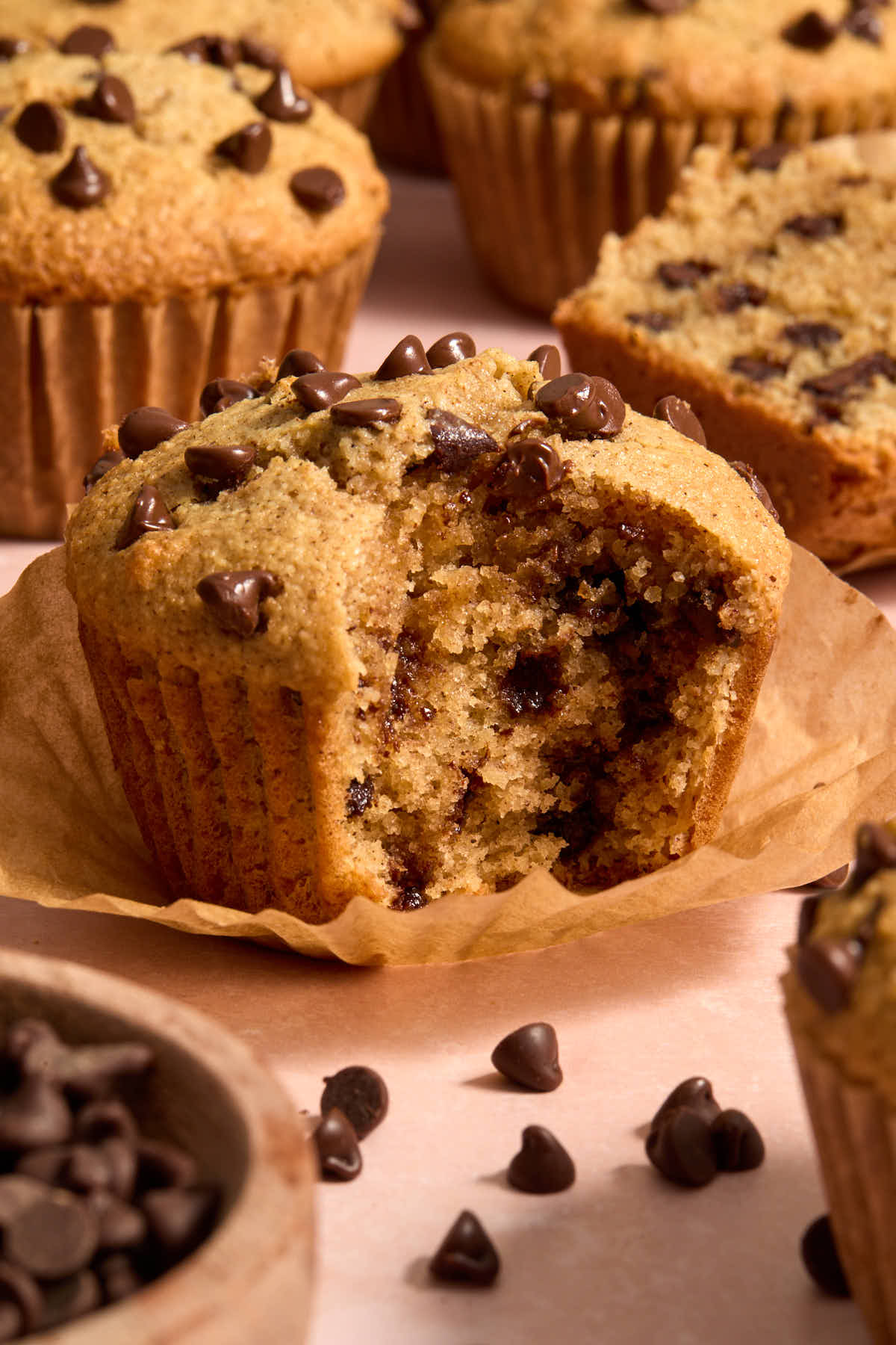 Side view of a muffin on its parchment liner with a bite taken.