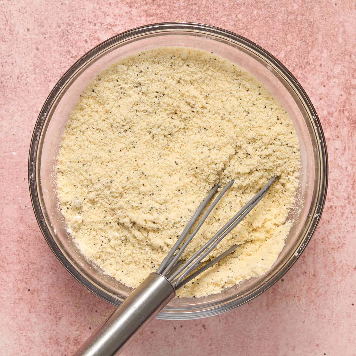 Almond flour and other dry ingredients whisked together in a glass bowl.