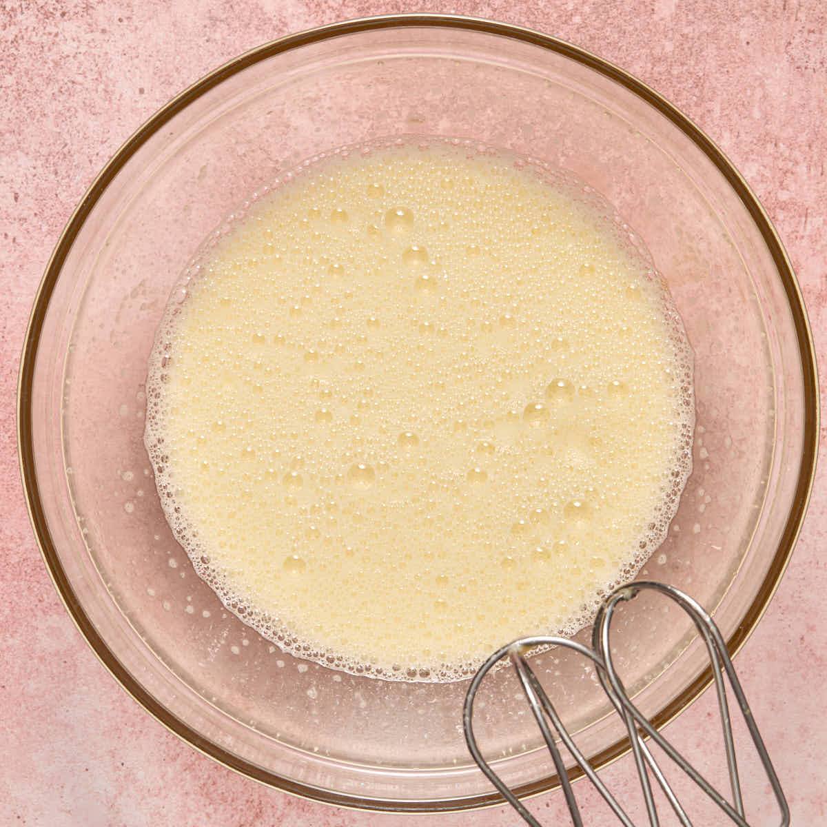 Eggs and sugar whipped together in a large bowl until bubbles formed on top.