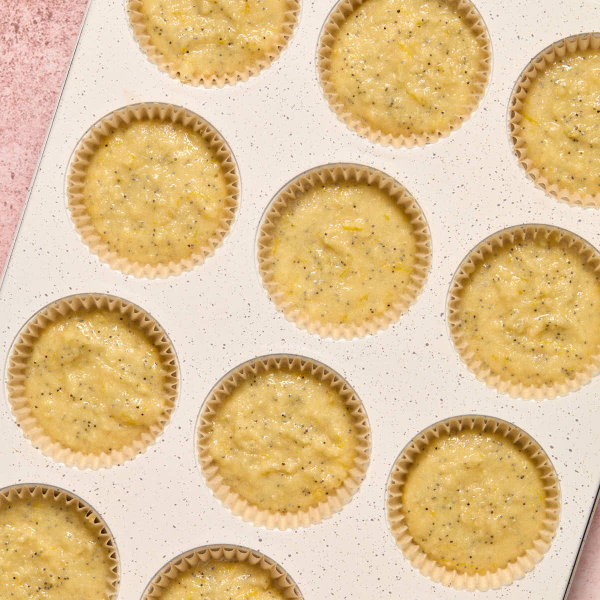 Cupcake batter divided into cupcake pan lined with parchment liners.