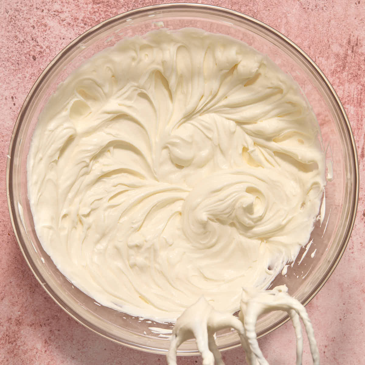 Cream cheese whipped cream mixed together in a bowl with beaters.