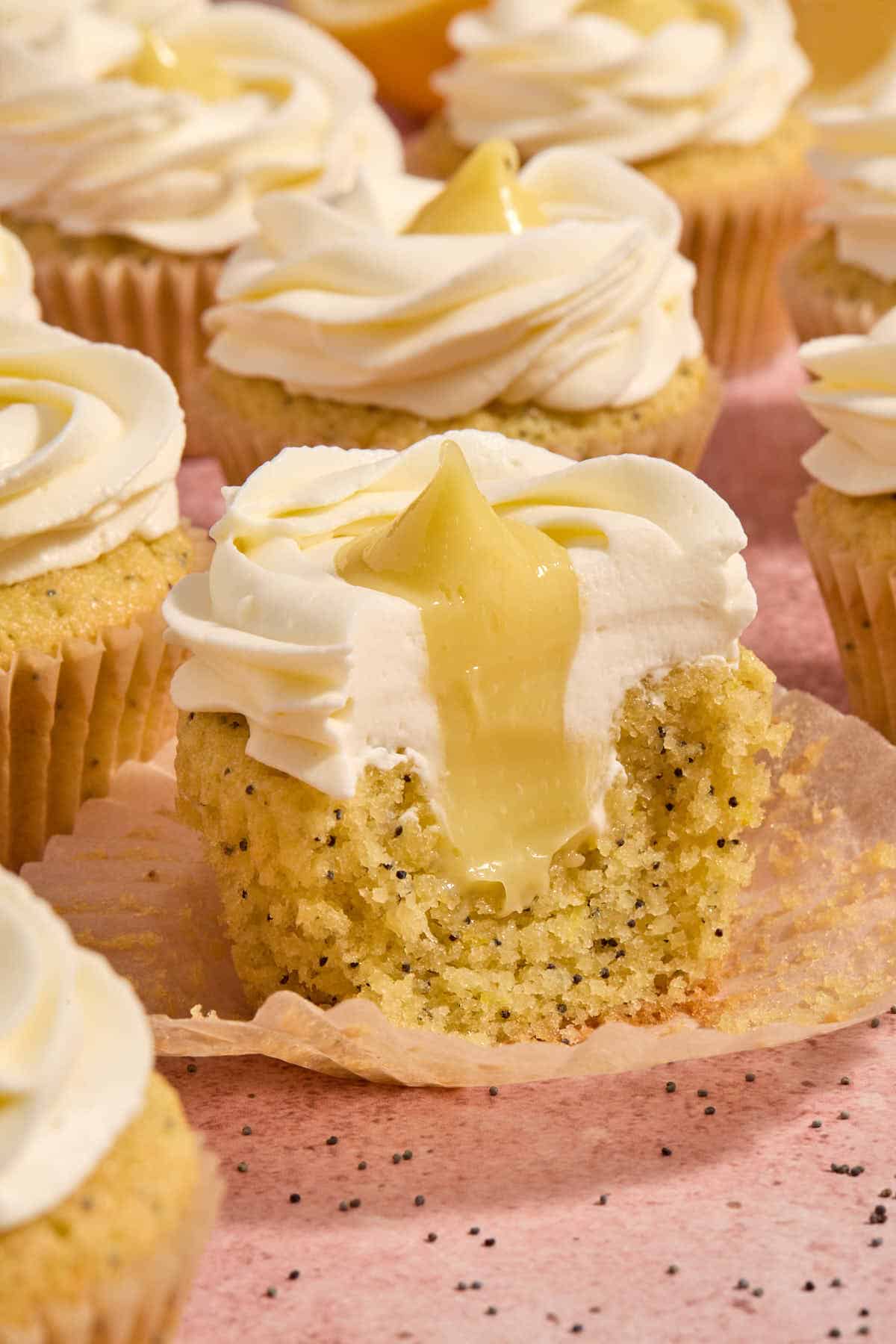 Cupcake on a parchment wrapper with some removed to show the lemon curd inside.