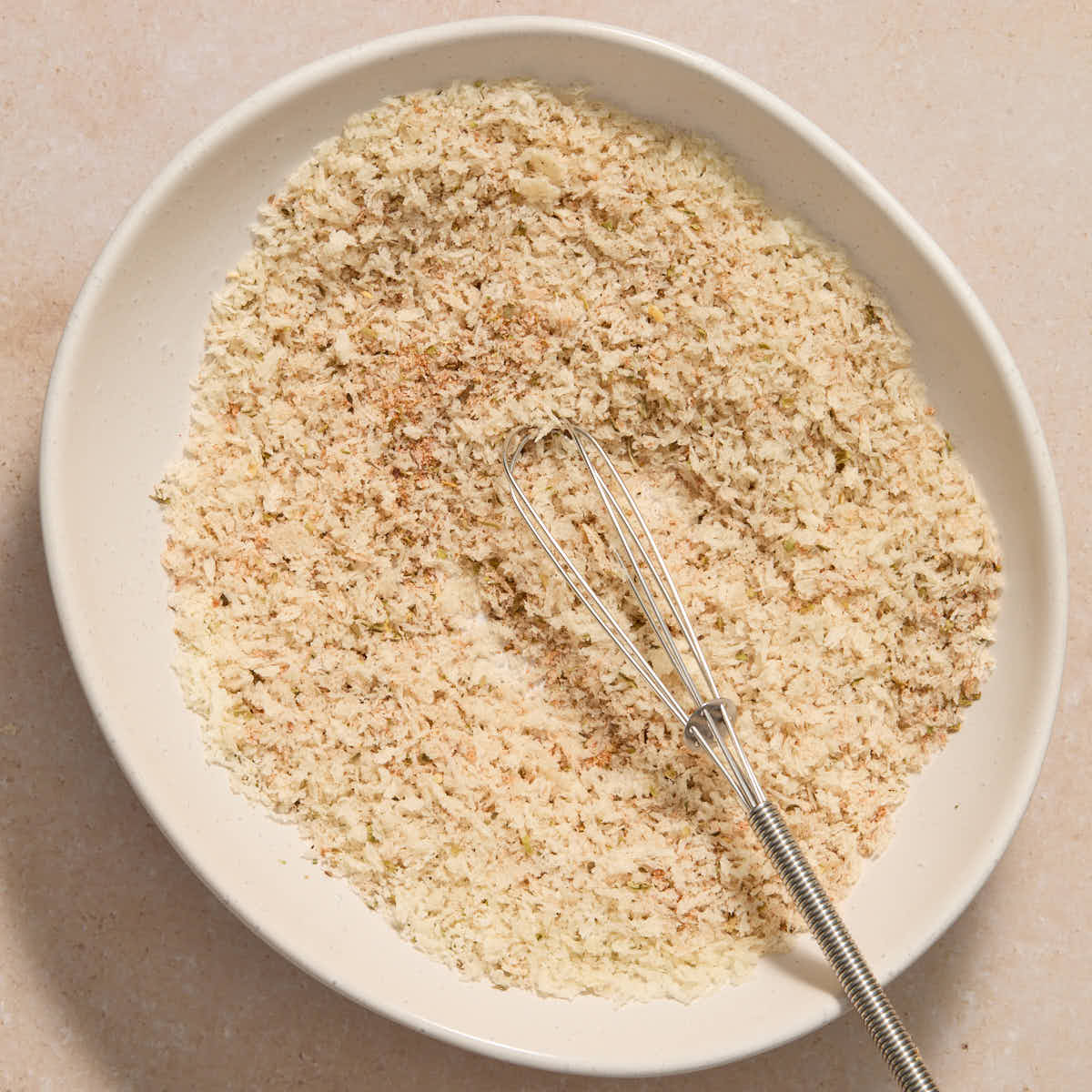 Panko crumbs and seasoning whisked together in a white bowl.