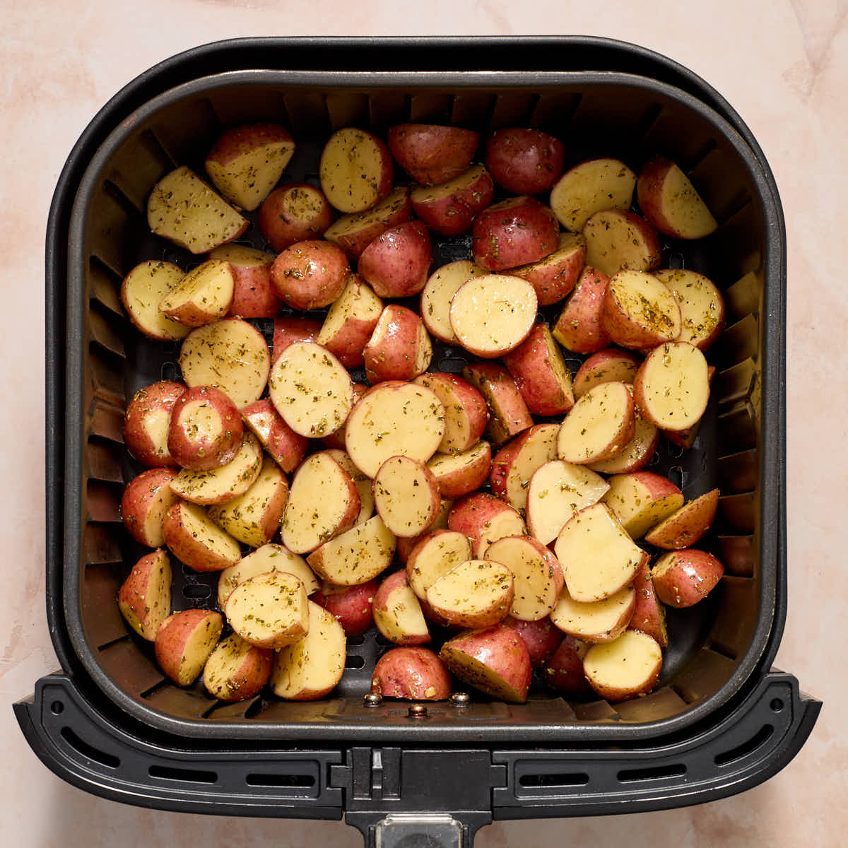 Seasoned potatoes in an air fryer basket.