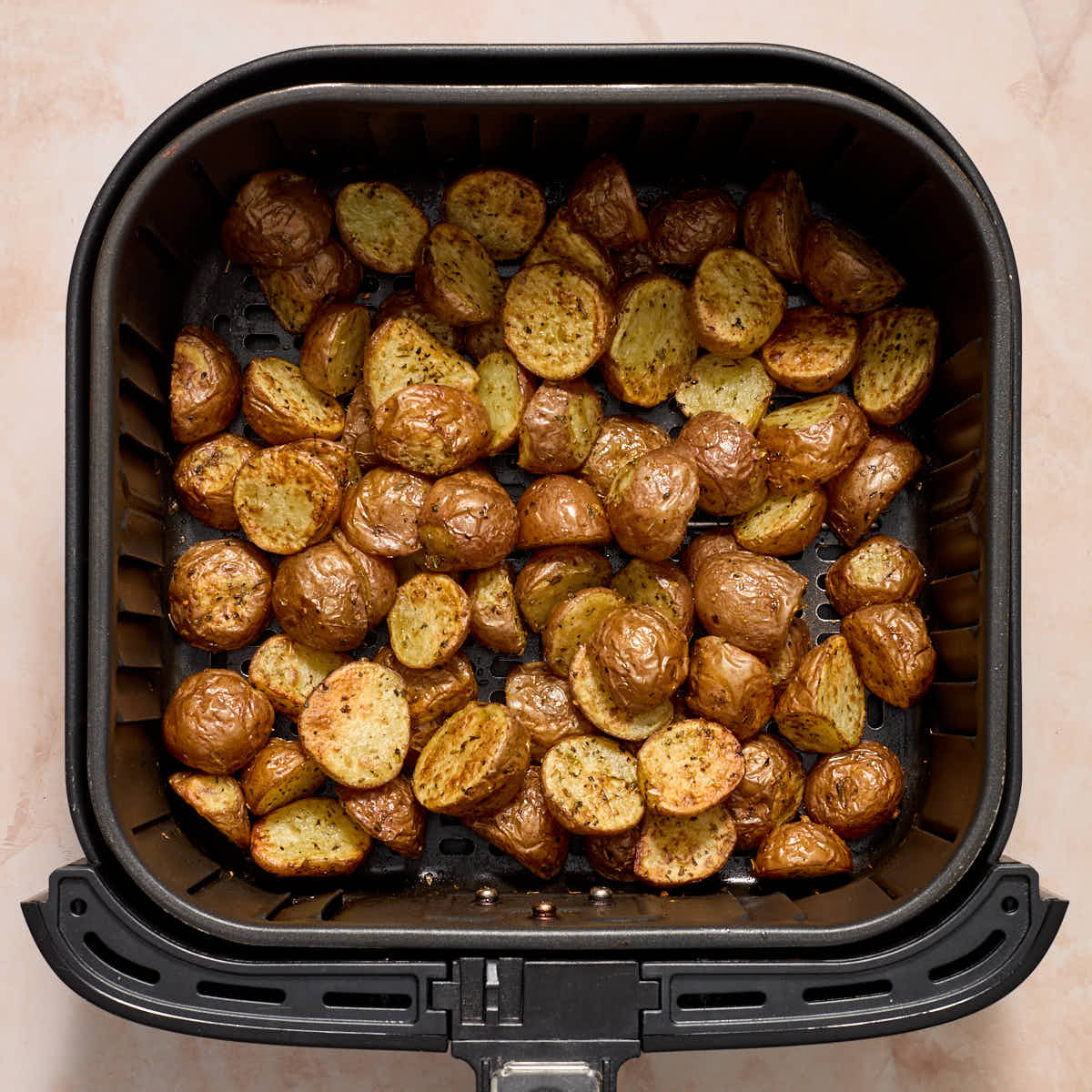 Air fried potatoes in an air fryer basket.