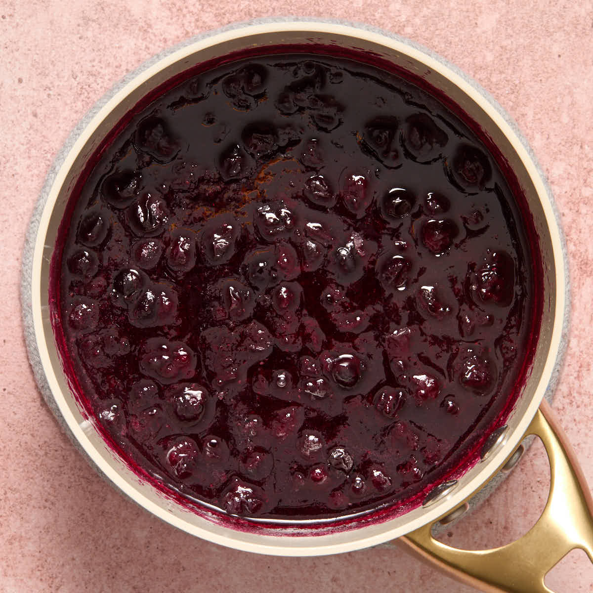Cooked blueberries in a small sauce pan.