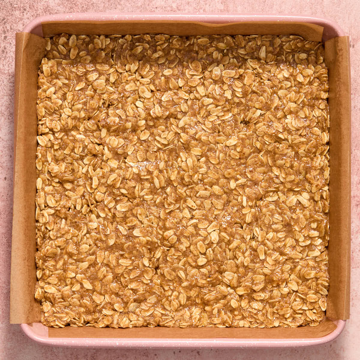 Some of the oat mixture pressed into the bottom of a square pan.