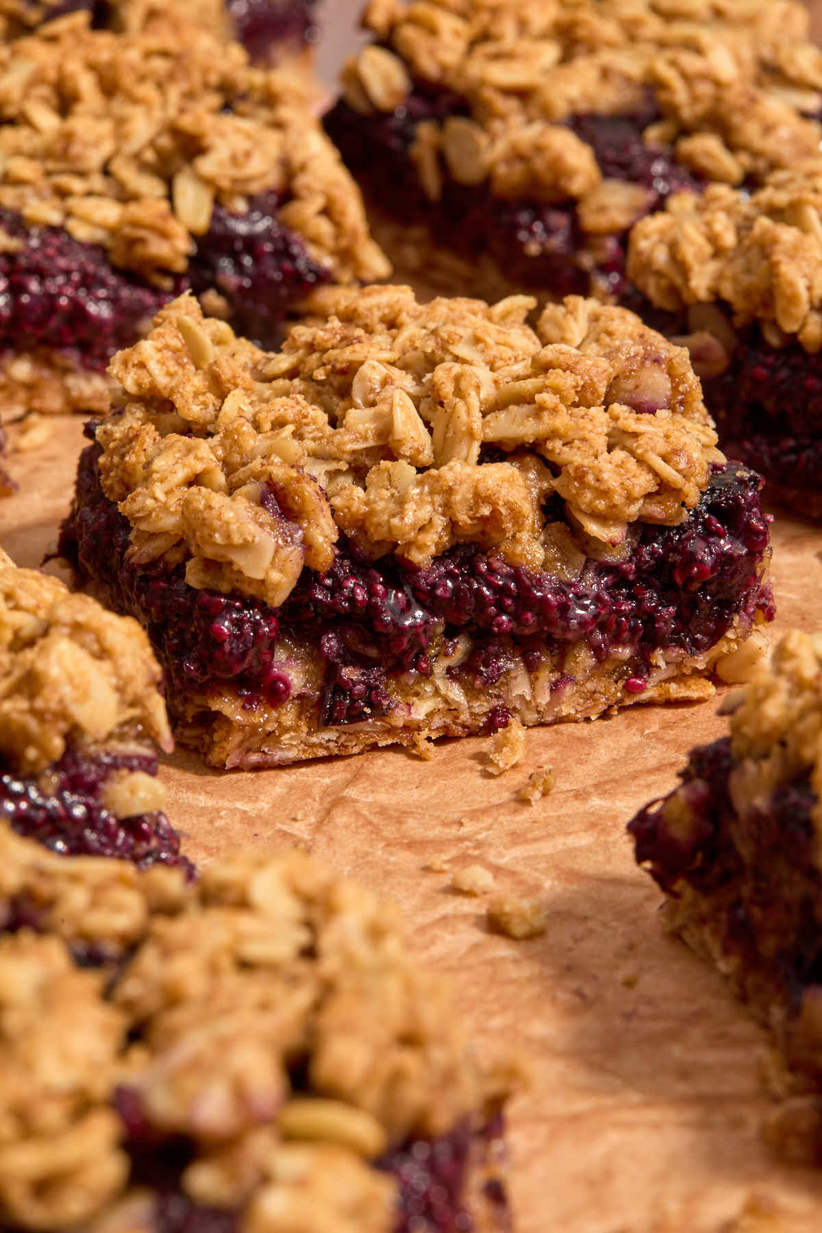 Breakfast bars on parchment paper, showing the blueberry chia jam filling.