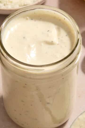 Caesar salad dressing in a glass jar.