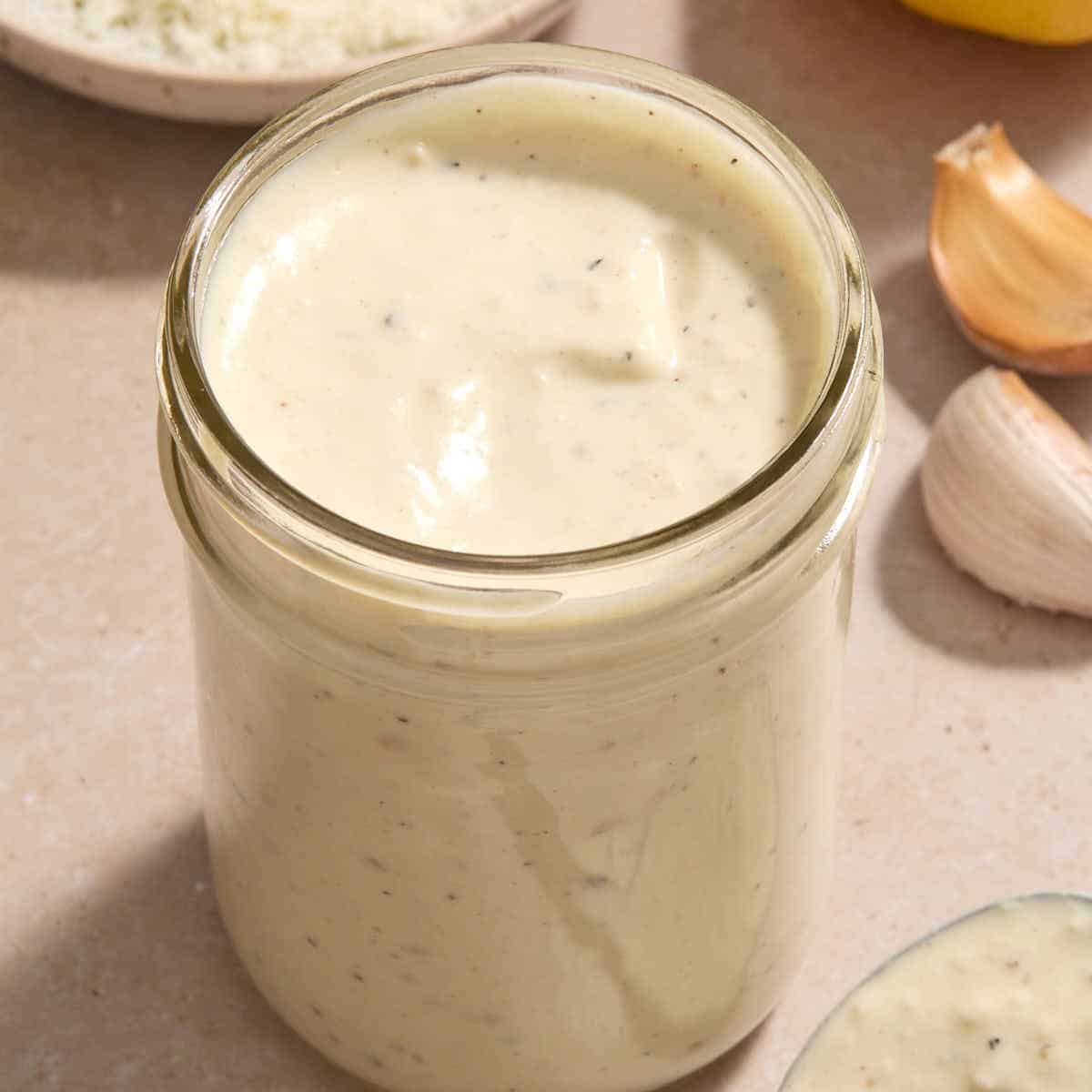 Caesar salad dressing in a glass jar.