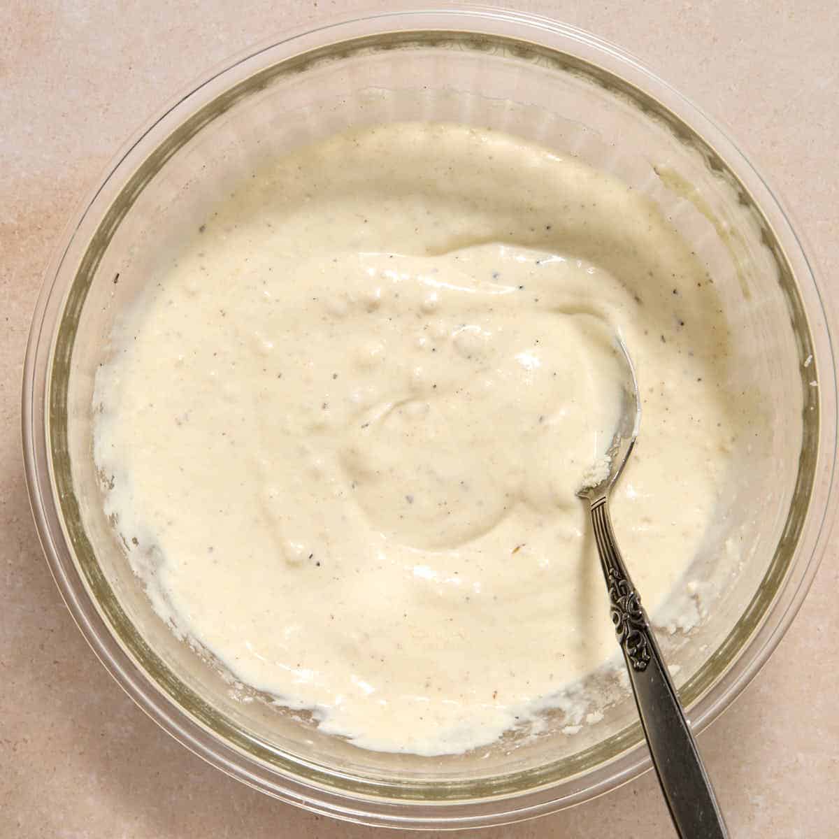Caesar dressing mixed together in a glass bowl.