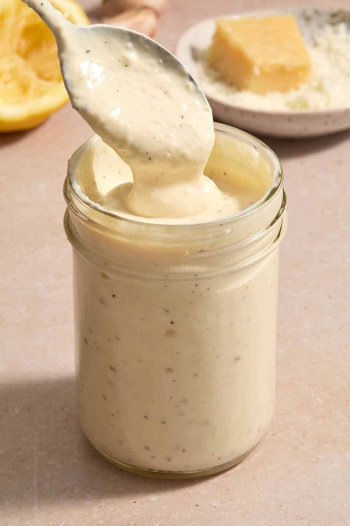 Spoonful of dressing being lifted out of a jar of dressing.