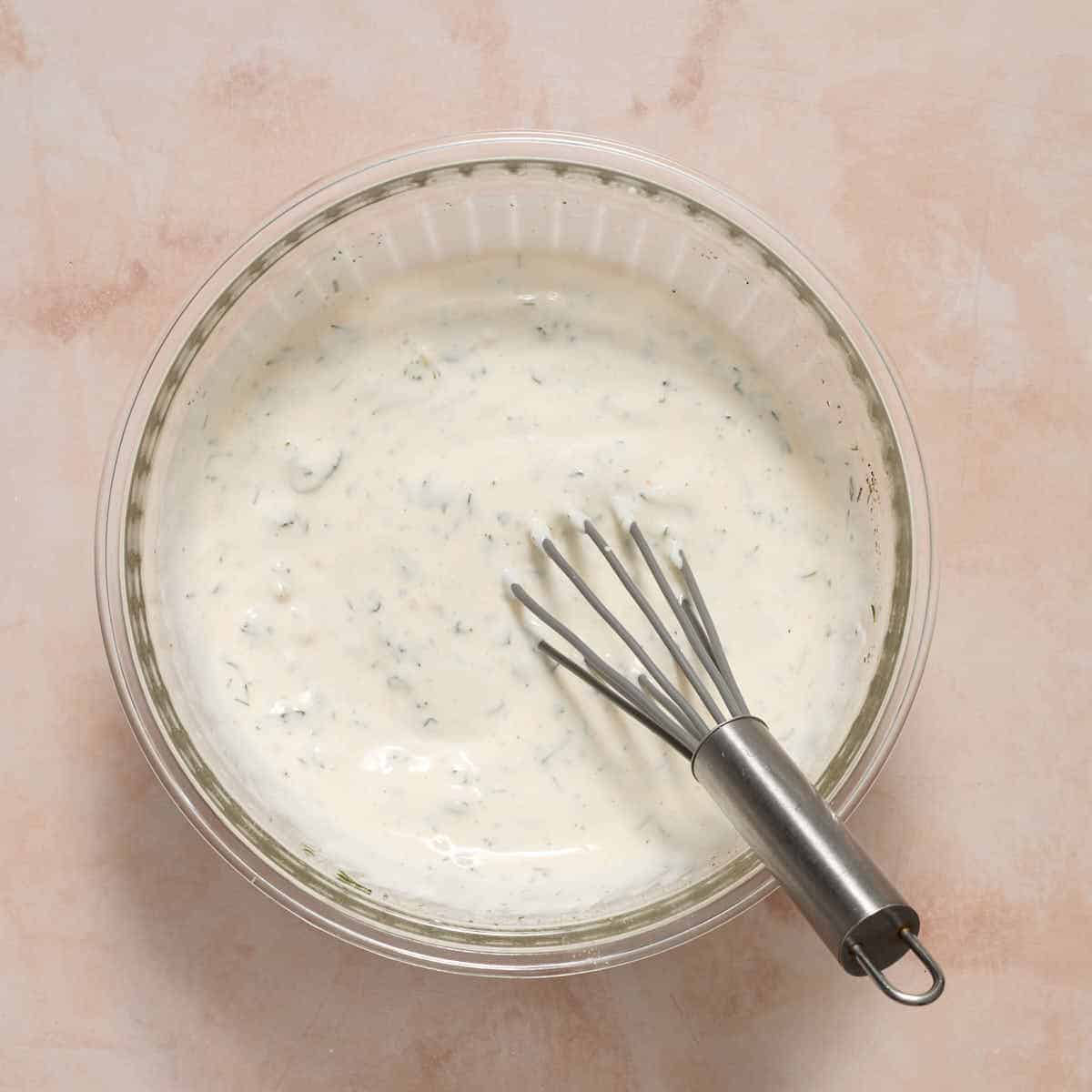Ranch dressing whisked together in a glass bowl.