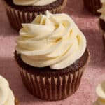 Whipped cream cheese frosting piped on top of a chocolate cupcake.