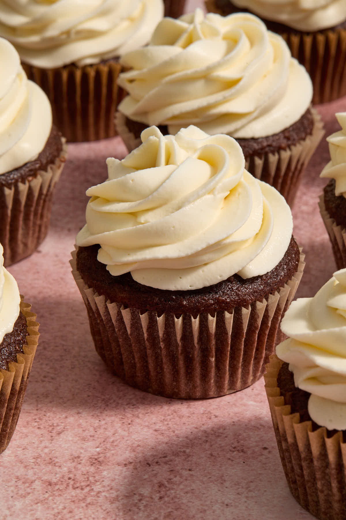 Frosting piped onto chocolate cupcakes in a swirl pattern.