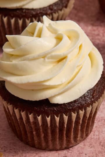 Whipped cream cheese frosting piped on top of a chocolate cupcake.
