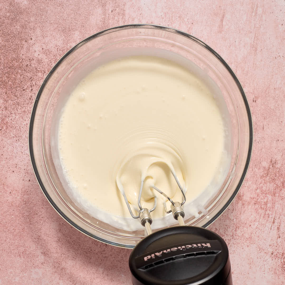 Handheld mixer beating the heavy cream into the cream cheese mixture.